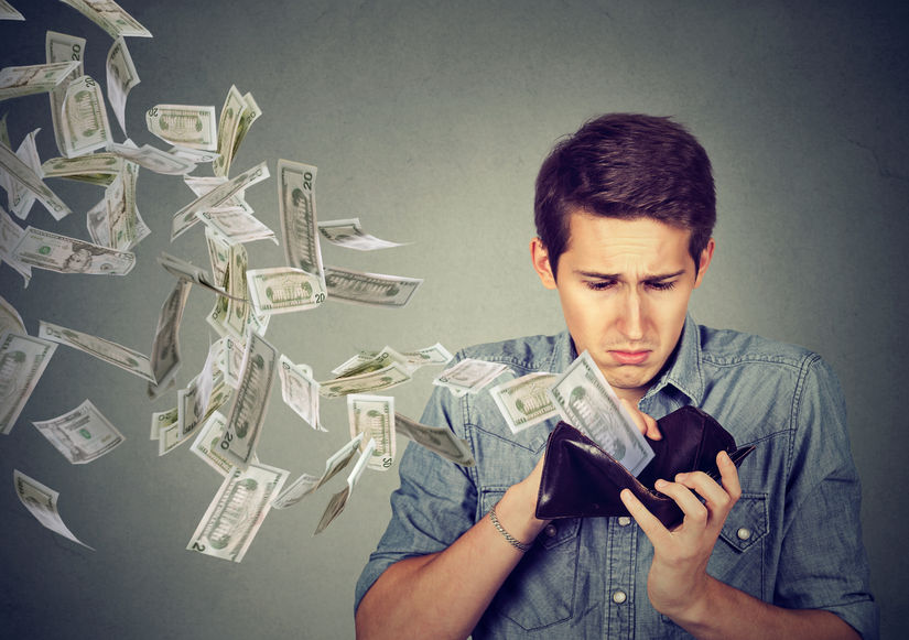 sad man looking at his wallet with money flying away due to high health coverage costs