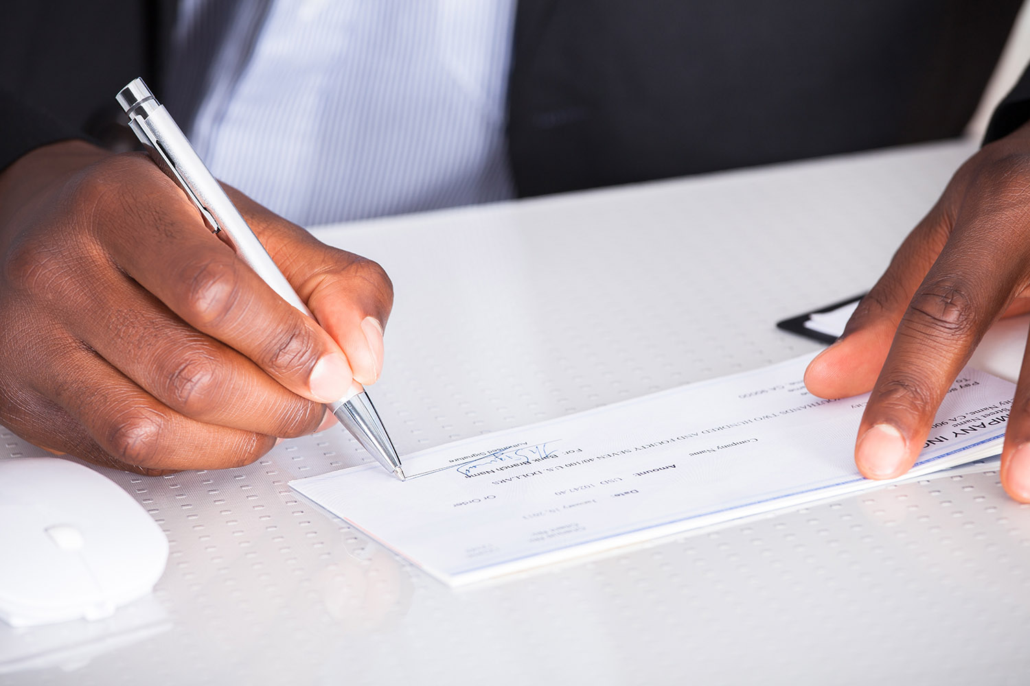 27 - close-up of human hand writing on cheque - CorpStrat