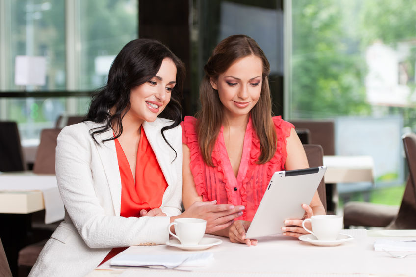 two female employees looking at iPad. smiling and looking positive in the workplace culture. 