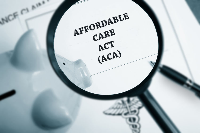 Magnifying glass over Affordable Care Act policy and business paperwork