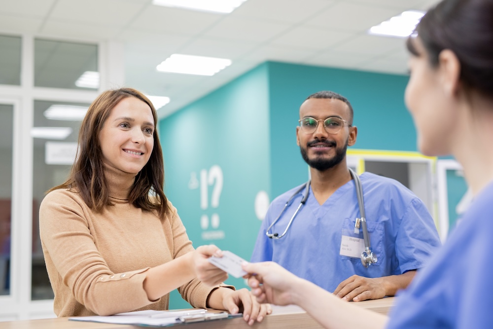Patient giving credit card to receptionist in clinics to pay for medical service